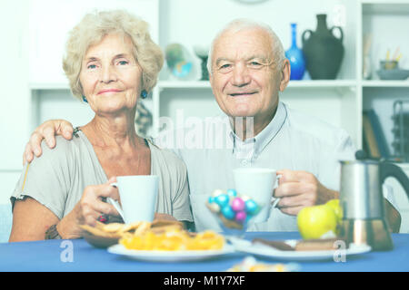 Portrait of happy mature couple having good time drinking tea in kitchen Stock Photo