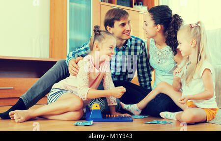 Cheerful happy family of four playing at lotto in domestic interior Stock Photo