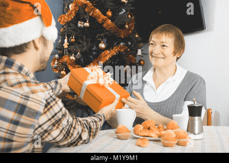 Mature mother and son gives gifts to each other for Christmas and Happy New Year Stock Photo