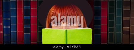 Woman reading in front of books Stock Photo