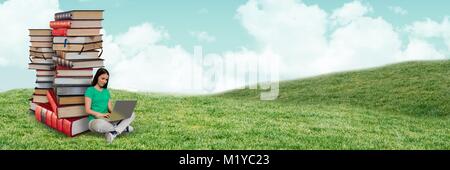 Woman using computer and piles of books outdoors Stock Photo
