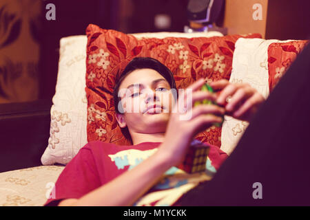 a boy sitting on the couch and playing with a rubik cube Stock Photo
