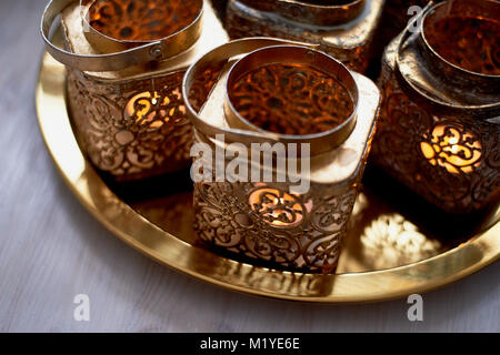 Eastern candlesticks with patterns in gold leaf with a burning candle.stand on a tray Stock Photo