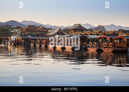 Traditional Chinese wooden recreation boats are moored along West Lake coast. Famous park in Hangzhou city, China Stock Photo