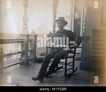 Antique circa 1905 photograph, elderly gentleman on his porch in military uniform with GAR badges. Location unknown, probably New England, USA. I have more photos of this family in Riggsville (now Robinhood), Maine in Sagadahoc County, USA. Stock Photo