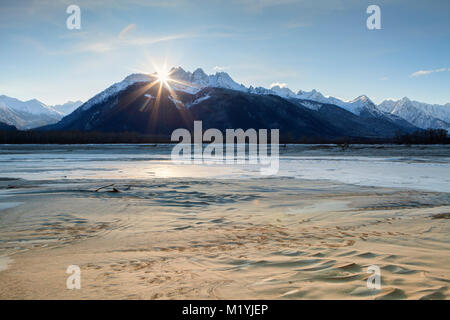 Sun going down behind Cathedral Peaks near the Chilkat river in Southeast Alaska on a windy cold winter day. Stock Photo