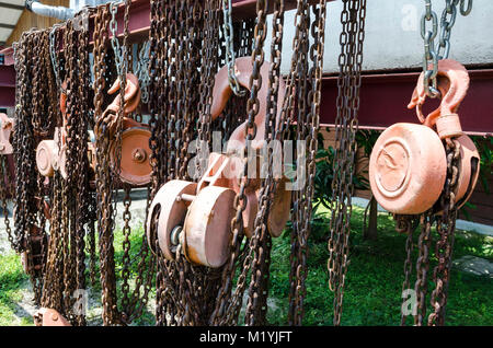 Old rusty metal hoist chain and pulley- Several old industrial chain and pulley Stock Photo