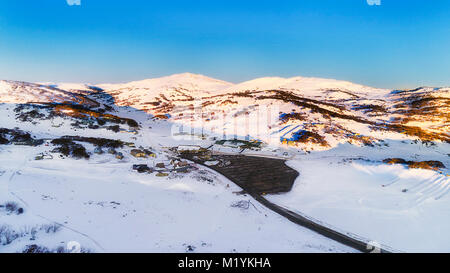 Sunrise over Perisher valley ski resort town in Snowy Mountains of Australia. High of winter skiining season with snow covered resort slopes lit by wa Stock Photo