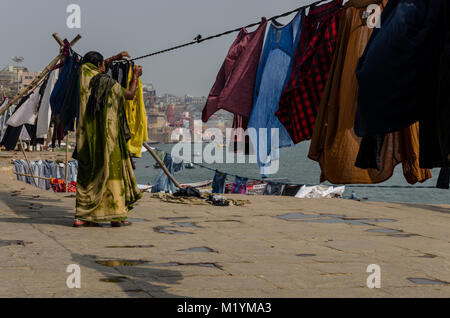 A Woman hangs the clothes to dry on the Ghats in Varanasi, Uttar Pradesh, India Stock Photo