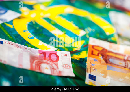 Low angle view of a euro sign in colorful pasty mixed acrylic color with applied euro banknotes. Stock Photo