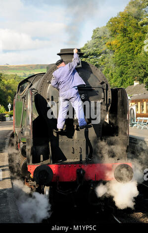 The driver/fireman of SR loco No 30926 'Repton' attends to the headlamp, prior to departure from Grosmont. Stock Photo