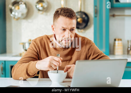 Pleasant nice man looking at the laptop screen Stock Photo