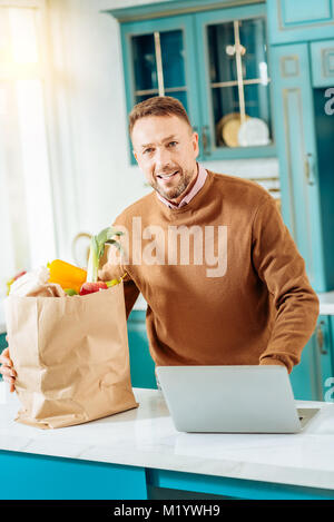 Nice positive man standing in the kitchen Stock Photo