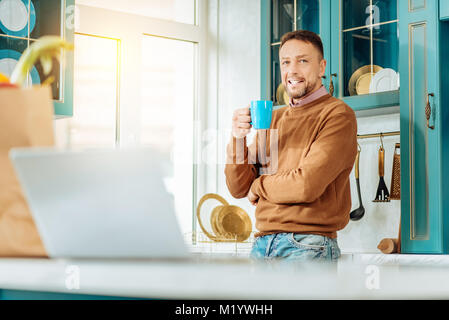 Joyful nice man having tea in the kitchen Stock Photo