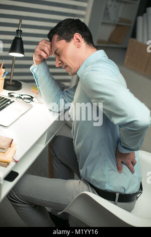 Tired male employee suffering from backache Stock Photo