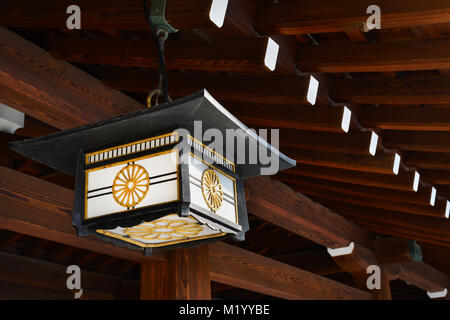 Old japanese lantern with chrysanthemum motif under a traditional wooden roof Stock Photo