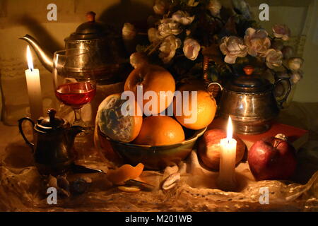 Still life inspired by the Dutch Masters. Classic still life with fruits, orange peel, old tea pot, books, candles, shells, wine glass and a knife. Stock Photo