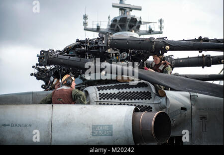 U.S. Marines assigned to the ‘Wolfpack’ of Heavy Marine Helicopter Squadron (HMH) 466, conduct maintenance on a CH-53E Super Stallion aboard the amphibious assault ship USS Bonhomme Richard (LHD 6) at White Beach, Okinawa, Japan, Feb. 1, 2018. The Bonhomme Richard is operating in the Indo-Asia-Pacific region as part of a regularly scheduled patrol and provides a rapid-response capability in the event of a regional contingency or natural disaster. (U.S. Navy photo by Mass Communication Specialist 2nd Class Diana Quinlan) Stock Photo