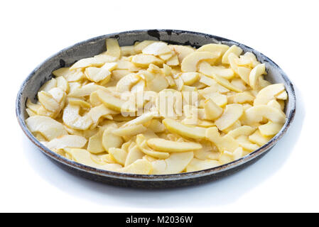 Phase of preparation of an apple pie. Baking tin with apples cut into thin slices on which the dough will be poured. White background Stock Photo