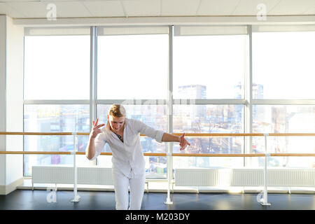 Young blonde dancer enjoys winning in white suit and makes warm  Stock Photo