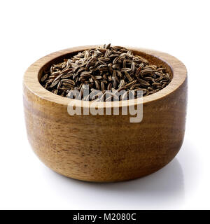 Dry caraway or cumin seeds in dark wood bowl isolated on white. Stock Photo