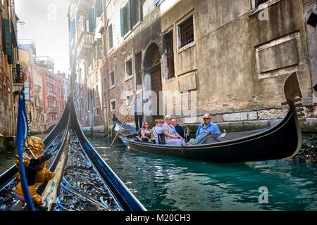 VENICE, ITALY - MAY 21, 2017: Tourists taking a ride on a gondola and beautiful old buildings seen from a gondola on the canals of Venice, Italy. Stock Photo