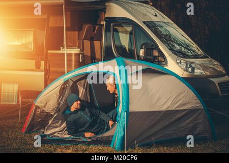 Romantic Tent and RV Camping Spot. Caucasian Couple Having Fun Far From the City. Stock Photo