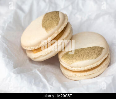 Salted caramel macarons with gold decoration in white tissue paper Stock Photo