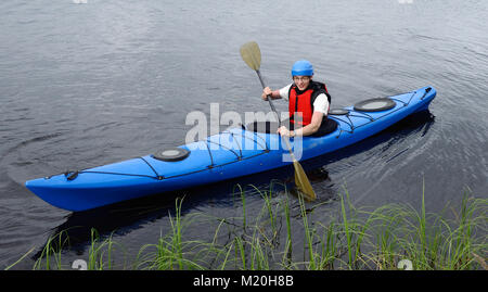 Cheerful young man kayaking on big lake Stock Photo