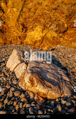 Golden cliffs, pebbles and rocks at Church Bay, Anglesey, Wales in summer sunshine Stock Photo