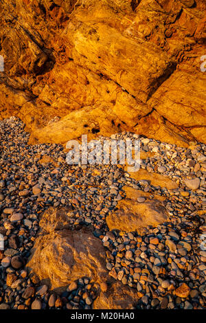 Golden cliffs, pebbles and rocks at Church Bay, Anglesey, Wales in summer sunshine Stock Photo