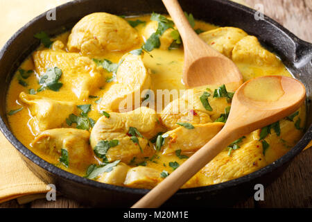 Spicy chicken in a sauce of coconut milk close-up in a frying pan. horizontal Stock Photo