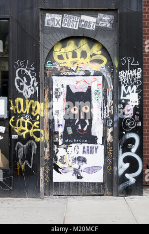 A doorway on Eighth Avenue below 14th St. in Manhattan with graffiti, stickers and posters. Stock Photo