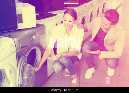 Young couple choosing washing machine in hypermarket and smiling Stock Photo