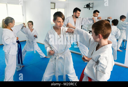 Serious positive teenagers practicing new karate moves in pairs in class Stock Photo