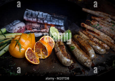 Sausage cooking on a brazier-grill. This new concept - three in one - combines the advantages of cooking with the plancha plus a barbecue and brazier. Stock Photo