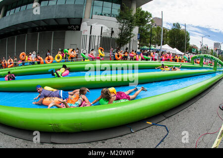 Atlanta, GA, USA - July 15, 2017:  Hundreds of people with innertubes enjoy participating in a giant waterslide at Slide The City in Atlanta, GA. Stock Photo