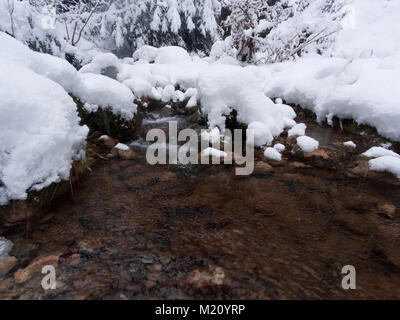 Clay-colored river in winter with snowed shore Stock Photo