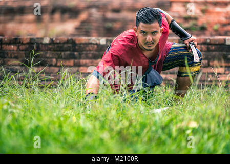 Ancient swordman in ancient soldier thai suite on kneel to the ground prepare for attack with swords. Stock Photo