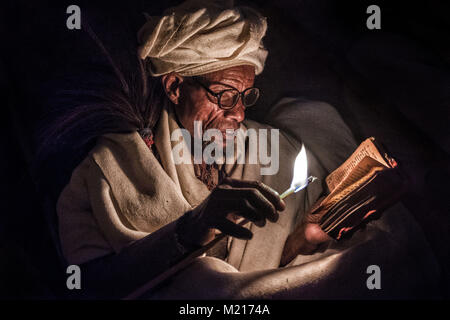 Lalibela, Amhara Region, Ethiopia. 6th Jan, 2018. A pilgrim praying with candle lit at night outside the Biete Medhane Alem (House of the Saviour of the World).During the first days of January, thousands of Ethiopian Orthodox Christian pilgrims go to the city of Lalibela to visit the ''New Jerusalem''. This holy city is composed of 11 interconnected churches carved by hand that are connected through a series of labyrinths and tunnels.The first days of January mark the celebration of Genna (also known as Ledet), which is the Christmas version of the Ethiopian calendar. During this celebra Stock Photo