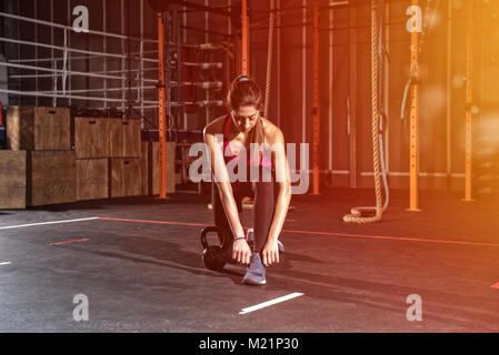 Athletic girl ready to start exercises with a kettlebell at the gym Stock Photo