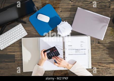 Elevated View Of A Businesswoman Calculating Invoice At Workplace Stock Photo