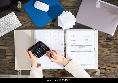 Elevated View Of A Businesswoman Calculating Invoice At Workplace Stock Photo