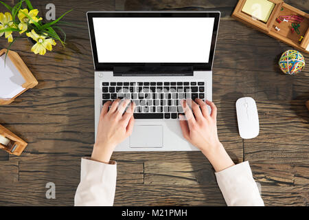 Elevated View Of A Female Hands Typing On Laptop Keypad Over The Wooden Desk Stock Photo
