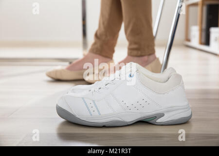 Pair Of A White Sport Shoes Besides Businesswoman's Legs In Office Stock Photo