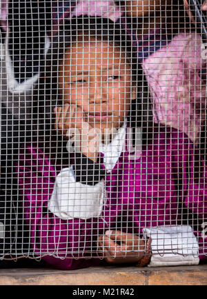 Prakhar Lhakhang, Bumthang, Bhutan.  Young Girl Looking through Kitchen Window Screen. Stock Photo