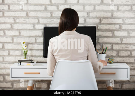Rear View Of A Businesswoman Using Computer At Workplace In Office Stock Photo