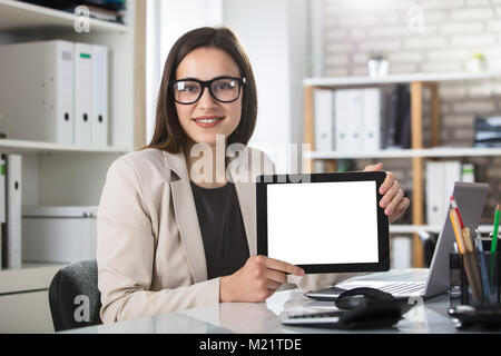 Close-up Of A Young Smiling Woman Showing Blank Screen On Digital Tablet At Workplace Stock Photo
