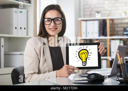 A Smiling Young Business Woman Showing Idea Concept On Digital Tablet In Office Stock Photo