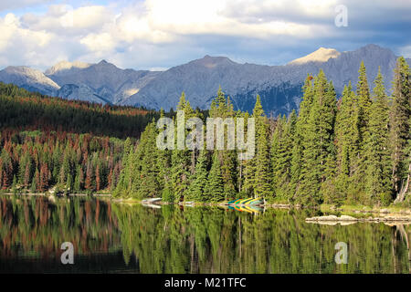 Canoes on a lake shore with mountains in the background. Stock Photo